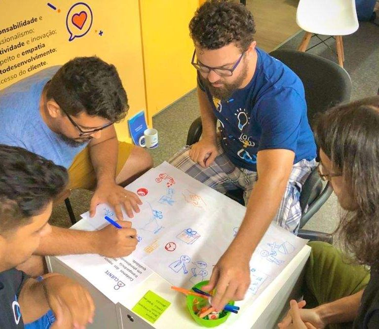 colaboradores da empresa realizam atividade reunidos em torno de uma mesa