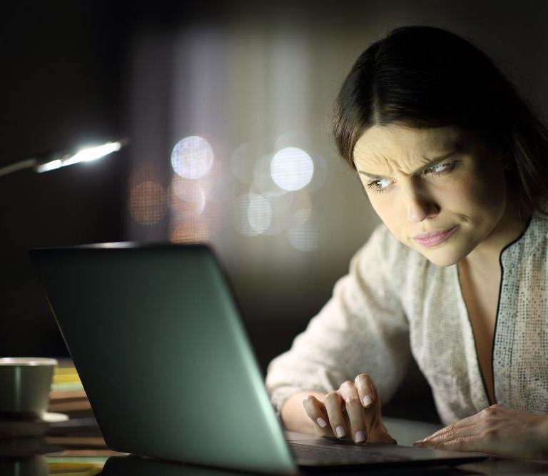 mulher olha para a tela do computador e desconfia de falsa vaga de emprego