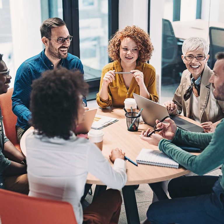 grupo de profisionais diversos sentados ao redor da mesa representam a importância da inteligência cultural para empresas
