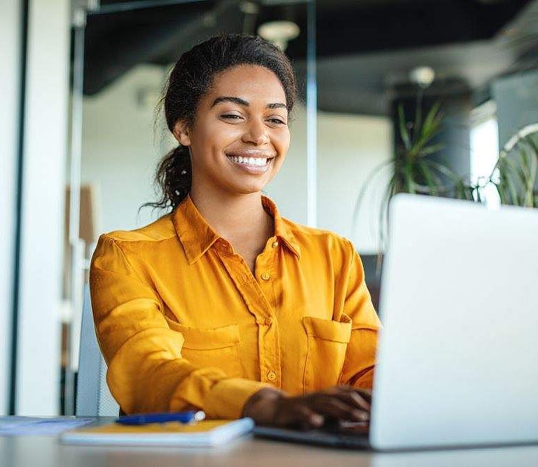 mulher trabalhando com expressão de satisfação representa os benefícios da análise de perfil comportamental