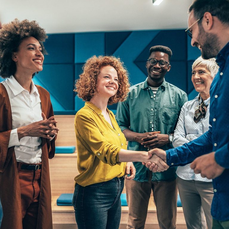 um grupo de pessoas recebe uma nova colaboradora em um onboarding de funcionários