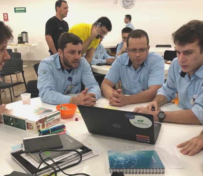 grupo de profissionais realiza atividade em grupo no computador durante ação de treinamento e desenvolvimento