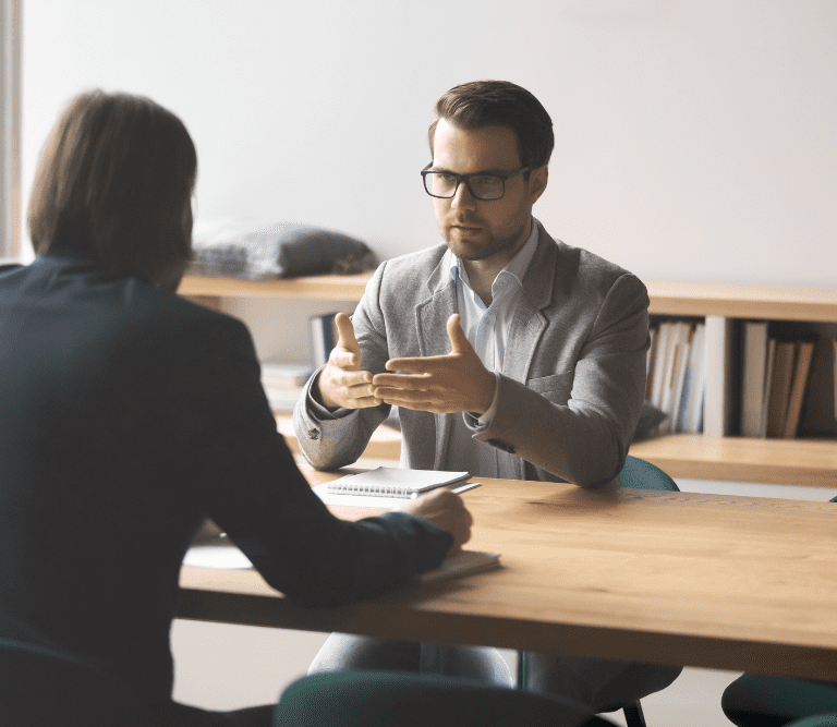 duas pessoas conversam em uma sala de reunião para ilustrar o que pode ser terceirizado no rh da sua empresa